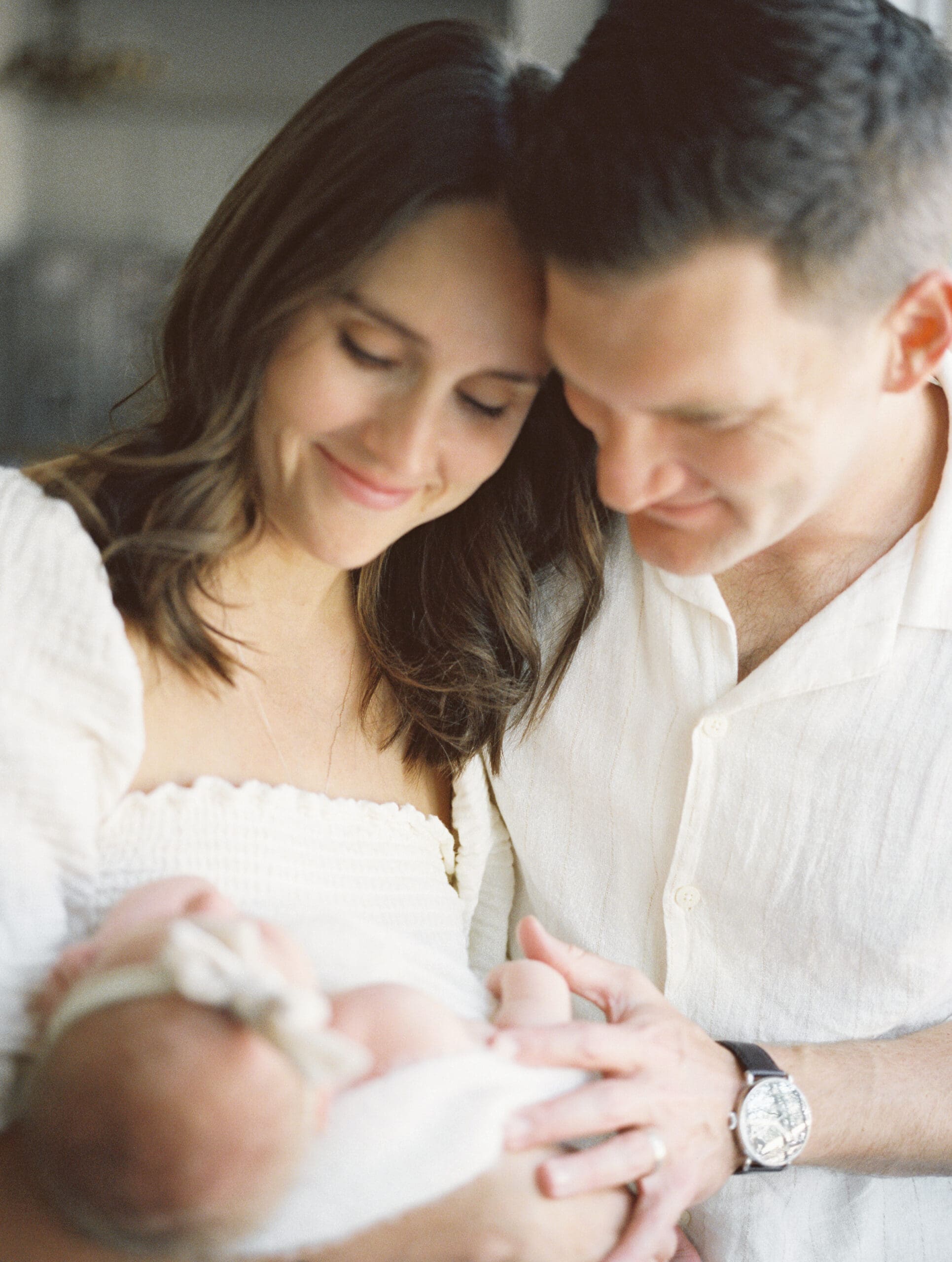 Parents admiring their newborn daughter during an in home family session in Argyle, Texas.