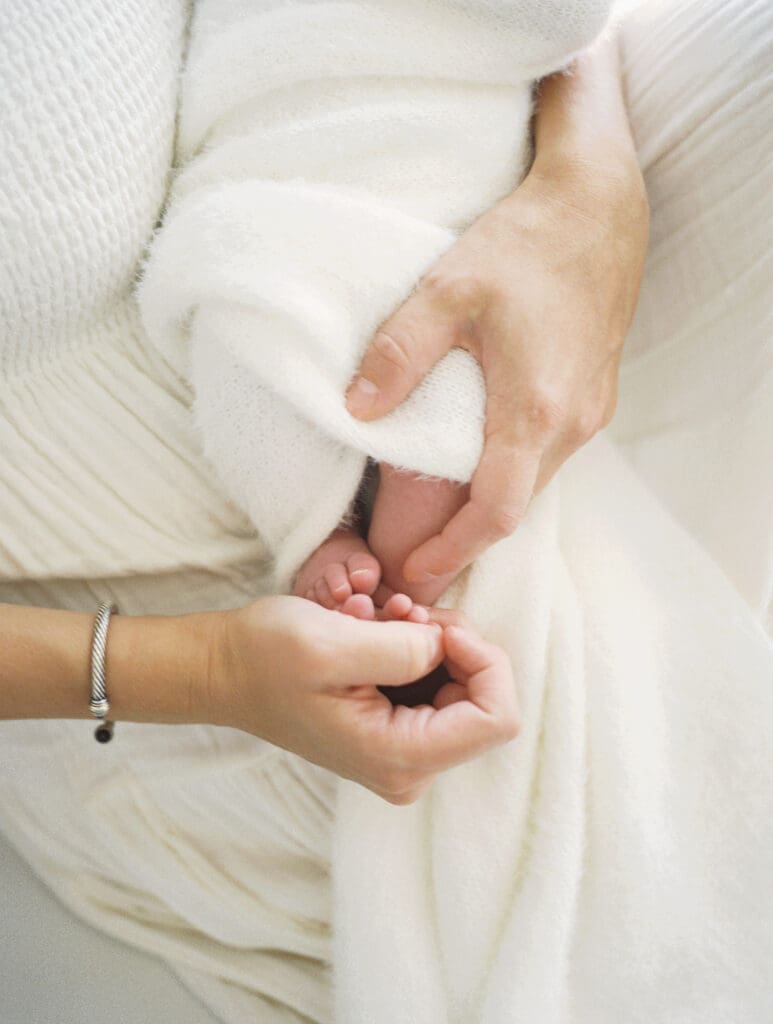 Mom holding her newborn baby girls foot in her hands.